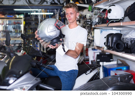 Motorcyclist is choosing helmet for motorbike 104300990