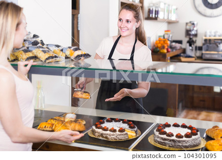 Bakery female worker with delicious pies and rolls on counter 104301095