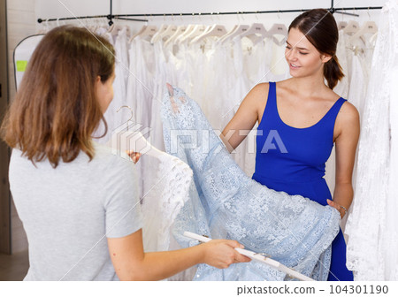 Consultant helping woman to choose bridal dress Consultant helping woman to choose bridal dress 104301190