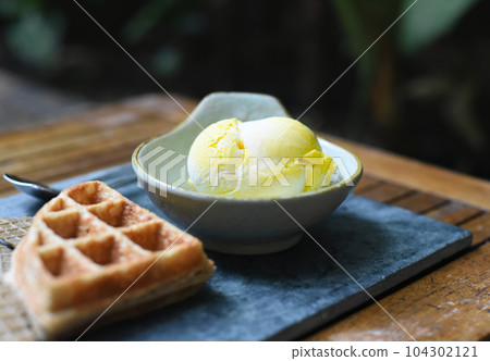 Scoop of mango organic ice cream  in a ceramic bowl on stone gray plate  Scoop of mango organic ice cream  in a ceramic bowl on stone gray plate  104302121