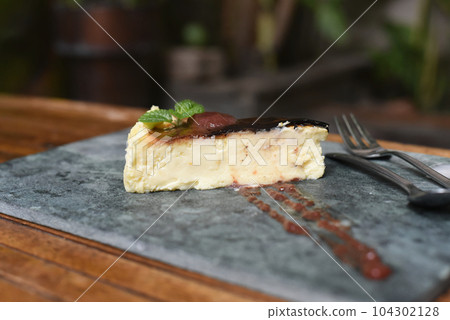 Burnt cheesecake on a stone plate with mint leaf 104302128