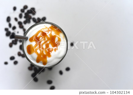 Ice caramel latte with coffee beans on wooden table Ice caramel latte with coffee beans on wooden table 104302134