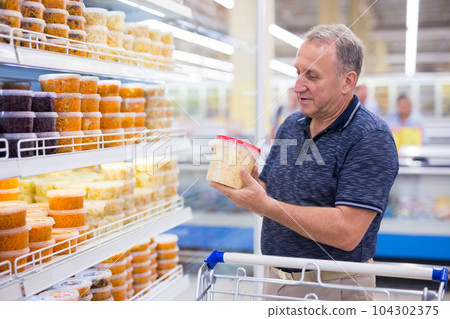 elderly retired man buying sauerkraut and pickles in grocery department of supermarket 104302375