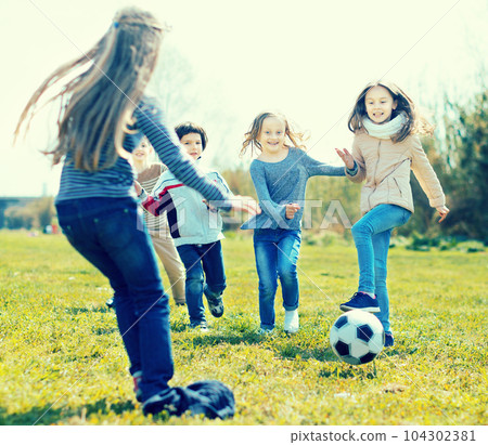 girls and boy playing soccer in park in autumn girls and boy playing soccer in park in autumn 104302381