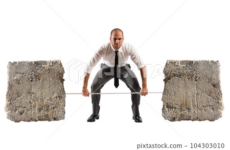 Powerful and determined businessman trains with a barbell with stones 104303010