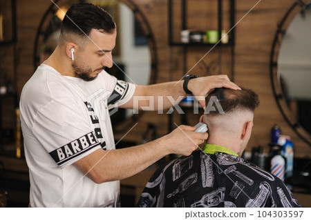 Back view of human hand hold trimmer and make hairstyle for man. Barbershop Back view of human hand hold trimmer and make hairstyle for man. Barbershop 104303597