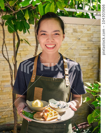 Vietnamese woman waitress serving Belgian waffles with scoops of organic ice cream in outdoor cafe Vietnamese woman waitress serving Belgian waffles with scoops of organic ice cream in outdoor cafe 104303666