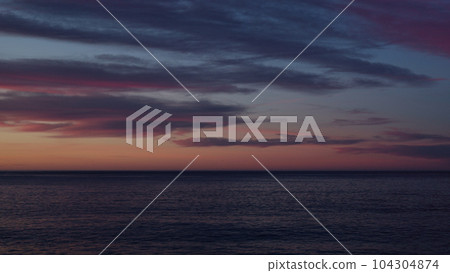 Beautiful sunset with purple clouds and flying birds over the sea Beautiful sunset with purple clouds and flying birds over the sea 104304874