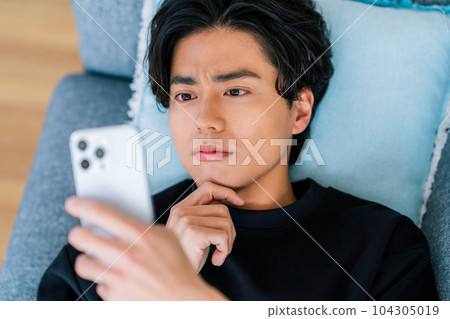 A young man operating a smartphone 104305019