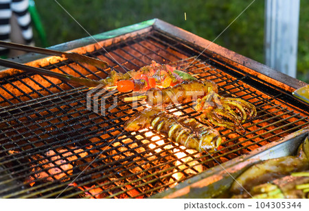 Many squids on a grill in vietnamese night market in food festival, process of cooking Many squids on a grill in vietnamese night market in food festival, process of cooking 104305344