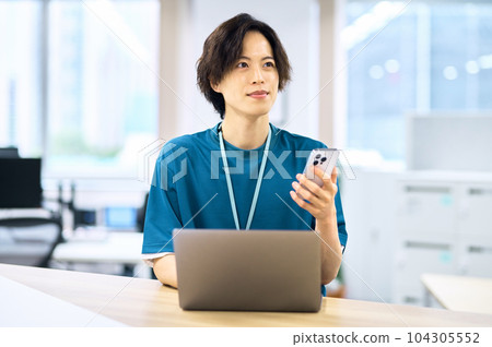 Young male engineer operating a smartphone Young male engineer operating a smartphone 104305552