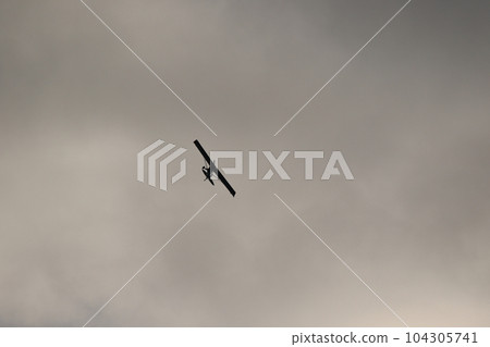 Small plane flying in the sky against dark clouds 104305741
