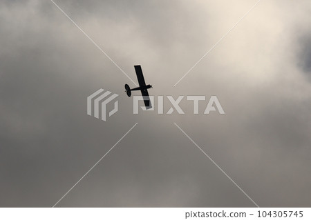 Small plane flying in the sky against dark clouds Small plane flying in the sky against dark clouds 104305745
