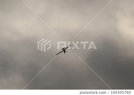Small plane flying in the sky against dark clouds 104305760