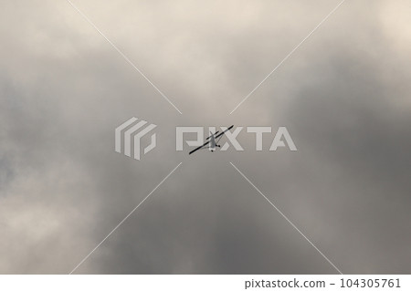 Small plane flying in the sky against dark clouds 104305761