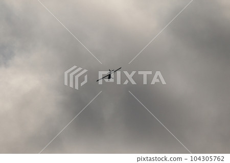 Small plane flying in the sky against dark clouds 104305762