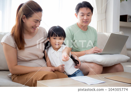 Happy family with mother teaching homework with daughter and father working with laptop on sofa. Happy family with mother teaching homework with daughter and father working with laptop on sofa. 104305774