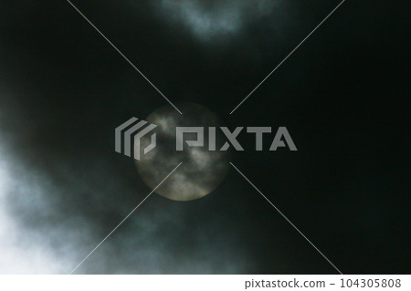 Sun disk behind backlit clouds 104305808