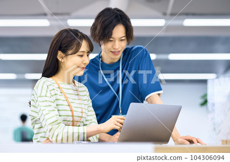 Young male and female engineers in plain clothes doing desk work Young male and female engineers in plain clothes doing desk work 104306094