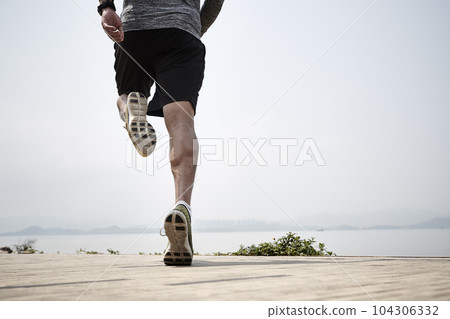 close-up shot of legs of an asian runner running by the sea, rear view 104306332