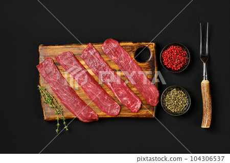 Overhead view of raw beef strips on black background Overhead view of raw beef strips on black background 104306537