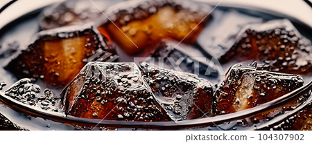 Cola with Ice. Close up of the ice cubes in cola water. Texture of carbonate drink with bubbles in glass. Cola soda and ice splashing fizzing or floating up to top of surface. Cold drink background. Cola with Ice. Close up of the ice cubes in cola water. Texture of carbonate drink with bubbles in glass. Cola soda and ice splashing fizzing or floating up to top of surface. Cold drink background. 104307902