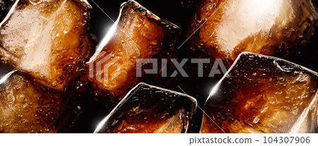 Cola with Ice. Close up of the ice cubes in cola water. Texture of carbonate drink with bubbles in glass. Cola soda and ice splashing fizzing or floating up to top of surface. Cold drink background. Cola with Ice. Close up of the ice cubes in cola water. Texture of carbonate drink with bubbles in glass. Cola soda and ice splashing fizzing or floating up to top of surface. Cold drink background. 104307906