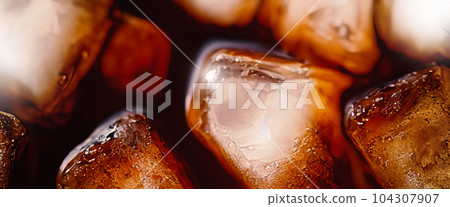 Cola with Ice. Close up of the ice cubes in cola water. Texture of carbonate drink with bubbles in glass. Cola soda and ice splashing fizzing or floating up to top of surface. Cold drink background. Cola with Ice. Close up of the ice cubes in cola water. Texture of carbonate drink with bubbles in glass. Cola soda and ice splashing fizzing or floating up to top of surface. Cold drink background. 104307907