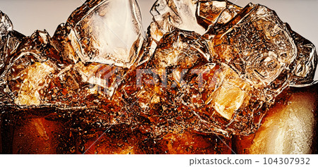 Cola with Ice. Close up of the ice cubes in cola water. Texture of carbonate drink with bubbles in glass. Cola soda and ice splashing fizzing or floating up to top of surface. Cold drink background. 104307932