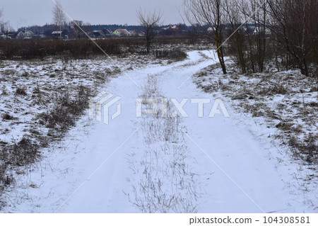 Road running through the field covered with snow. Road running through the field covered with snow. 104308581