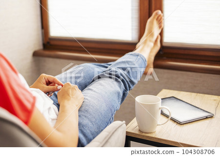 Young beautiful woman in casual wear sitting in armchair with cup of hot coffee 104308706