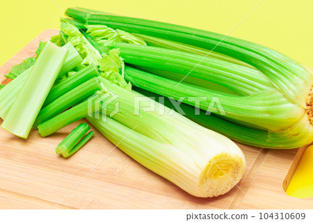 Fresh Celery Stem and Chopped Celery Sticks on Wooden Cutting Board 104310609