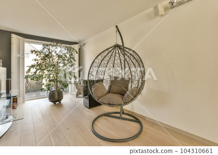 a living room with a hanging chair in the middle and a tv on the right side, next to an open door a living room with a hanging chair in the middle and a tv on the right side, next to an open door 104310661