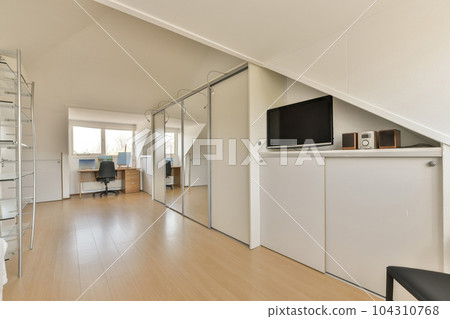 a living room with wood floors and white walls, an office desk in the corner is visible on the right side 104310768