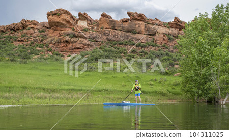 senior male paddler on a touring stand up paddleboard on lake in Colorado foothills - Horsetooth Reservoir near Fort Collins 104311025