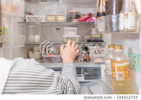 [A housewife taking out a tapper from the refrigerator] 104312733