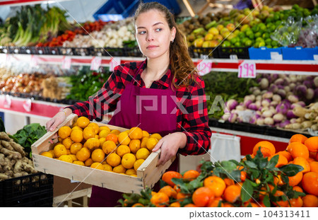 Young smiling woman salesman carrying box with yellow plums Young smiling woman salesman carrying box with yellow plums 104313411