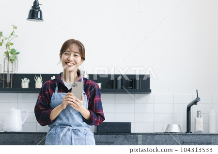 A woman in an apron standing in the kitchen A woman in an apron standing in the kitchen 104313533
