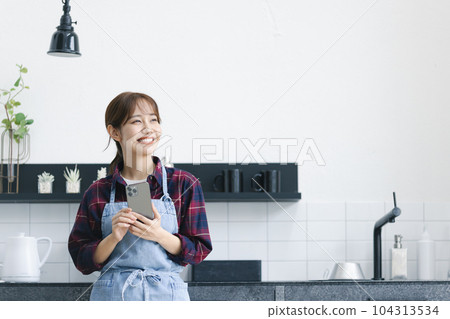 站立在廚房裡的圍裙的一名婦女 104313534