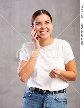 Cheerful young woman talking on mobile phone 104314320