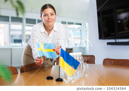 Businesswoman setting flags of Ukraine and Sweden on negotiating table Businesswoman setting flags of Ukraine and Sweden on negotiating table 104314364