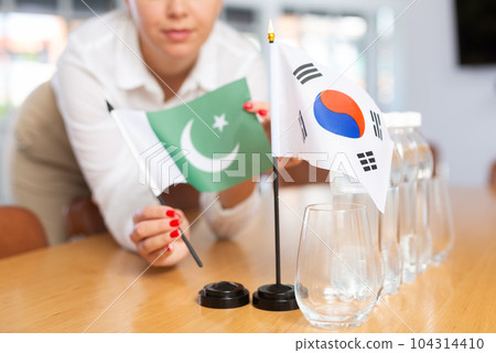 Female employee of the delegation sets flags of countries of South Korea and Pakistan on the table before start of negotiations Female employee of the delegation sets flags of countries of South Korea and Pakistan on the table before start of negotiations 104314410