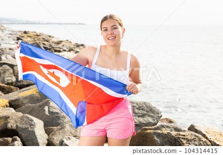 National flag of North korea. Beautiful woman with North korea flag on beach. National flag of North korea. Beautiful woman with North korea flag on beach. 104314415