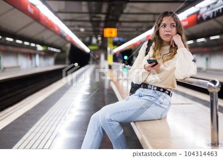 Young attractive girl in jeans waiting for subway train on a platform 104314463