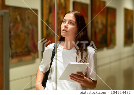 Girl visitor looks at the exhibit in the museum, located behind the glass 104314482