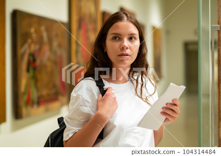 Portrait of a girl standing in a museum next to an exhibit, located in a glass cabinet 104314484