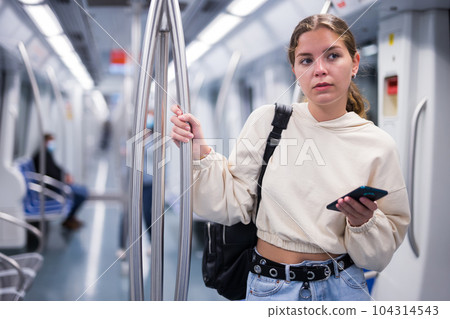 Portrait of a pensive girl with a mobile phone on a subway train 104314543