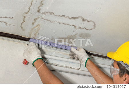 Worker fix leaking pipe in ceiling ,close-up of a stain on the ceiling. Worker fix leaking pipe in ceiling ,close-up of a stain on the ceiling. 104315037