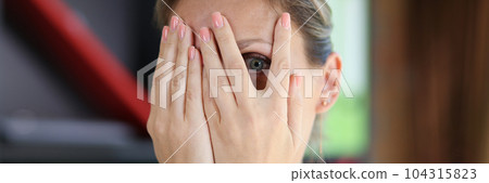 Shocked or scared woman looking through fingers 104315823