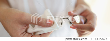 Woman wiping glasses with white cleaning napkin 104315824